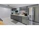 Galley kitchen features gray cabinets, stainless appliances, and a breakfast bar overlooking the living area at 20191 Rutherford Ave, Port Charlotte, FL 33952