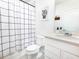 Bright bathroom featuring a shower with checkered curtain, a toilet and a sink at 29922 Marquette Ave, Wesley Chapel, FL 33545
