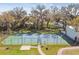 Aerial view of community tennis court surrounded by mature trees and lush grass on a bright sunny day at 302 Lake Parsons Grn # 201, Brandon, FL 33511