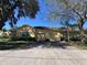 Beautiful tan home featuring an attached two-car garage, mature trees, and a paved driveway at 6359 Timberly Ln, Zephyrhills, FL 33542