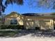 Beautiful tan home featuring an attached two-car garage, mature trees, and a paved driveway at 6359 Timberly Ln, Zephyrhills, FL 33542