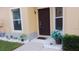 Inviting front entryway with a decorative potted plant and a dark brown front door and trim at 6359 Timberly Ln, Zephyrhills, FL 33542