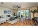 Bright living room with wood floors, ceiling fan, sliding glass doors, and stylish furnishings at 720 Earls Ct, Safety Harbor, FL 34695