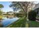 Scenic view of pond with lush green grass, mature trees, and reflections of the beautiful surrounding houses at 720 Earls Ct, Safety Harbor, FL 34695