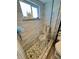Beautiful tiled shower with glass door, decorative tiling, and rock floor at 8911 Blind Pass Rd # 220, St Pete Beach, FL 33706