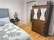 Bedroom with hardwood floors showcasing a dresser with glass front cabinets at 8911 Blind Pass Rd # 220, St Pete Beach, FL 33706