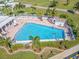 Aerial view of community pool with lounge chairs, a patio area, mature trees, and lush landscaping at 14336 93Rd Ave, Seminole, FL 33776