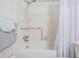 Neutral bathroom featuring a tub, shower, and safety bar, paired with classic white tiling at 2042 Australia W Way # 66, Clearwater, FL 33763