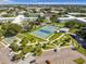 Aerial view of the community's blue tennis courts, picnic tables, and parking in a lush green setting at 2042 Australia W Way # 66, Clearwater, FL 33763