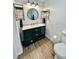 Bathroom featuring stylish dark vanity with a round mirror and wood-look flooring at 34344 Timberland Blvd, Wesley Chapel, FL 33543