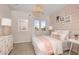 Bright bedroom features a white bed, light pink accent wall, and beach-themed decor, creating a serene and inviting space at 37236 Clinch Cir, Zephyrhills, FL 33540