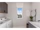 Bright laundry room featuring modern appliances, basin sink, and view of the neighborhood through a large window at 37236 Clinch Cir, Zephyrhills, FL 33540