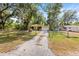 Charming yellow home featuring a single-car garage and a driveway, surrounded by mature trees and a fenced yard at 3908 Alafia Blvd, Brandon, FL 33511