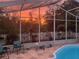 Beautiful screened-in pool, with a colorful sunset sky providing a serene background at 4029 Savage Station Cir, New Port Richey, FL 34653