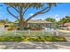 Charming gray home featuring a large tree, white picket fence, and meticulously maintained landscaping at 4135 Beach Se Dr, St Petersburg, FL 33705