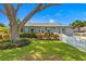 Beautifully landscaped front yard with a large tree shading a well-maintained gray brick house and white picket fence at 4135 Beach Se Dr, St Petersburg, FL 33705