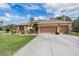 Charming single-story home with a well-manicured lawn, mature landscaping, and an attached three-car garage at 5088 Championship Cup Ln, Spring Hill, FL 34609