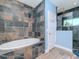 Bathroom featuring tiled walls, a soaking tub, a glass-enclosed shower, and blue accent walls at 5526 14Th S Ave, Gulfport, FL 33707
