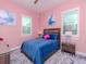 Bright bedroom with pink walls and light-filtering shutters, featuring a blue quilted bedspread at 5526 14Th S Ave, Gulfport, FL 33707