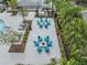 Aerial view of the outdoor lounging area with two fire pits, surrounded by Adirondack chairs and landscaped with palm trees at 7147 Forest Mere Dr, Riverview, FL 33578