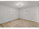 Bedroom with updated light fixture, light wood look floors, and two windows at 7480 Hobson Ne St, St Petersburg, FL 33702