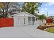 Charming single-story home featuring a gray exterior, a palm tree, a well-manicured lawn, and a red fence at 7480 Hobson Ne St, St Petersburg, FL 33702