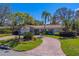 Charming single-story home with brick driveway, mature trees, a tile roof, and a manicured lawn on a sunny day at 809 Royal Dr, Largo, FL 33770