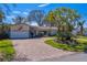 Beautiful single-story home featuring a curved paver driveway, mature trees and well-maintained landscaping at 809 Royal Dr, Largo, FL 33770