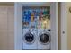 Stacked laundry area behind folding doors features modern washer and dryer with white cabinets and shelving at 809 Royal Dr, Largo, FL 33770