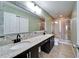 This bathroom has dual sinks with granite countertops, a light green wall color, and a tiled shower at 8842 Turnstone Haven Pl, Tampa, FL 33619