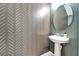 Stylish powder room features a pedestal sink, modern faucet, and patterned accent wall at 8842 Turnstone Haven Pl, Tampa, FL 33619