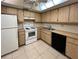 A well-lit kitchen features light wood cabinets, white appliances, and a tiled floor at 9221 Repondo Pl, New Port Richey, FL 34655