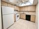 A well-lit kitchen features light wood cabinets, white appliances, and a tiled floor at 9221 Repondo Pl, New Port Richey, FL 34655