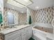 Bright bathroom features double vanity, granite countertop, soaking tub, and vibrant floral wallpaper at 9718 Tiffany Oaks Ln # 12, Tampa, FL 33612