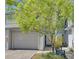 Two story home with a garage and lush green tree in the front yard, providing shade and curb appeal at 9718 Tiffany Oaks Ln # 12, Tampa, FL 33612