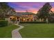 Sprawling house at dusk with manicured lawn, landscaping, walkway, and a warm, inviting ambiance at 9902 Menander Wood Ct, Odessa, FL 33556