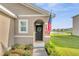 Inviting entryway with American flag, a wreath, and lush landscaping leading to the front door at 10864 Penny Gale Loop, San Antonio, FL 33576