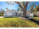 Charming single-story home featuring a manicured lawn, mature tree, and stylishly designed facade with an attached garage at 1100 Webb Dr, Clearwater, FL 33755