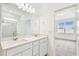 Bathroom with a double sink vanity with white cabinets, subway tile shower, and view to bedroom at 1226 Mumford Ct, Zephyrhills, FL 33540