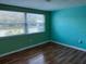 Empty bedroom with teal walls, wood floors and a large double window at 12607 Blackberry Row, Hudson, FL 34667