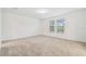 An empty bedroom with neutral carpeting, a ceiling light, and a bright window at 12614 Glenn Creek Dr, Riverview, FL 33569