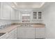 Updated kitchen with stainless steel sink, white cabinets, modern fixtures, and mosaic backsplash at 131 Bluff View Dr # 409, Belleair Bluffs, FL 33770