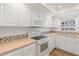 Bright kitchen with white appliances and cabinets, mosaic backsplash, and modern countertops at 131 Bluff View Dr # 409, Belleair Bluffs, FL 33770
