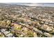 An aerial view of a residential neighborhood with mature trees and a glimpse of the ocean in the distance at 1510 Lakeside Dr, Dunedin, FL 34698