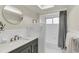 Neutral bathroom with a gray vanity, round mirror, shower with gray curtain, and tiled walls at 1510 Lakeside Dr, Dunedin, FL 34698