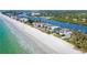 Aerial view of stunning beach homes along white sandy beach with tropical vegetation and tranquil water views at 20256 Gulf Blvd, Indian Shores, FL 33785