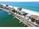 Coastal homes line a pristine beach, interspersed with docks and lush, tropical vegetation at 20256 Gulf Blvd, Indian Shores, FL 33785