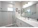 Modern bathroom with a glass shower, marble countertop, large mirror, and framed nautical art at 20256 Gulf Blvd, Indian Shores, FL 33785