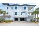 Three-story house featuring a garage, palm trees, and well-maintained landscaping at 20256 Gulf Blvd, Indian Shores, FL 33785