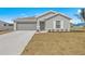 Gray home exterior featuring a two-car garage, manicured lawn, and well-lit entrance at 23343 Van Buren Ave, Port Charlotte, FL 33981